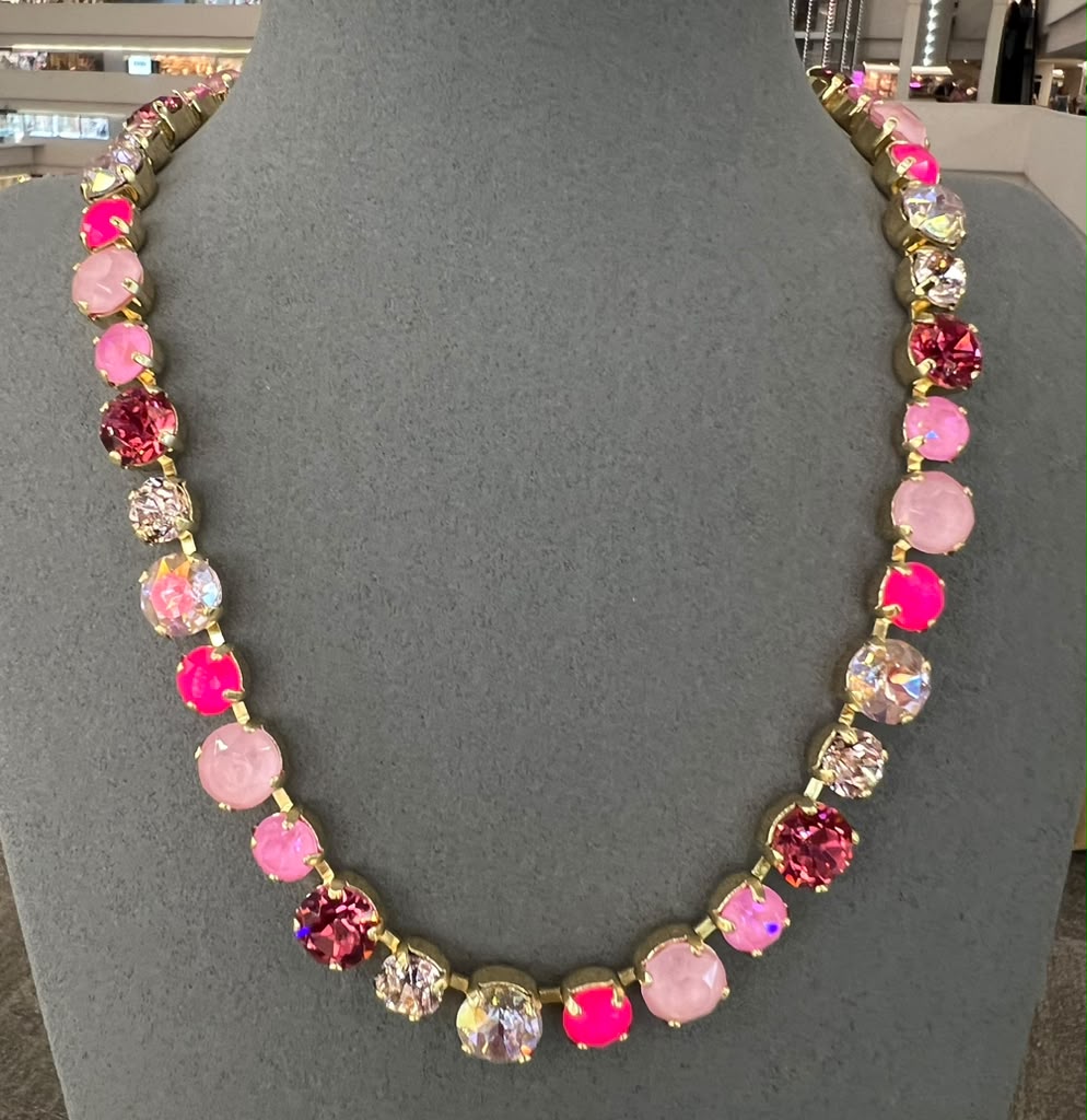 BEHROZ Catching Compliments necklace with pink, red and clear crystals in gold settings displayed on gray bust