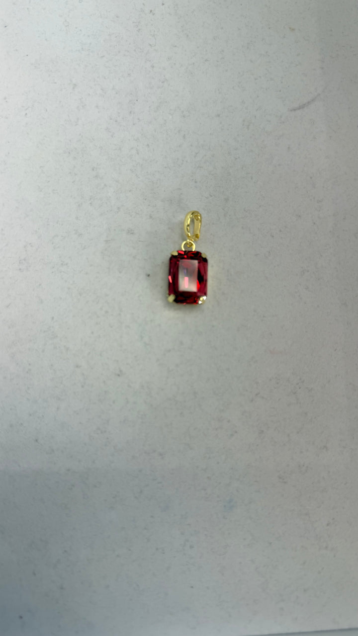 Small rectangular crimson red faceted gemstone pendant charm in a gold four-prong setting with oval bail.