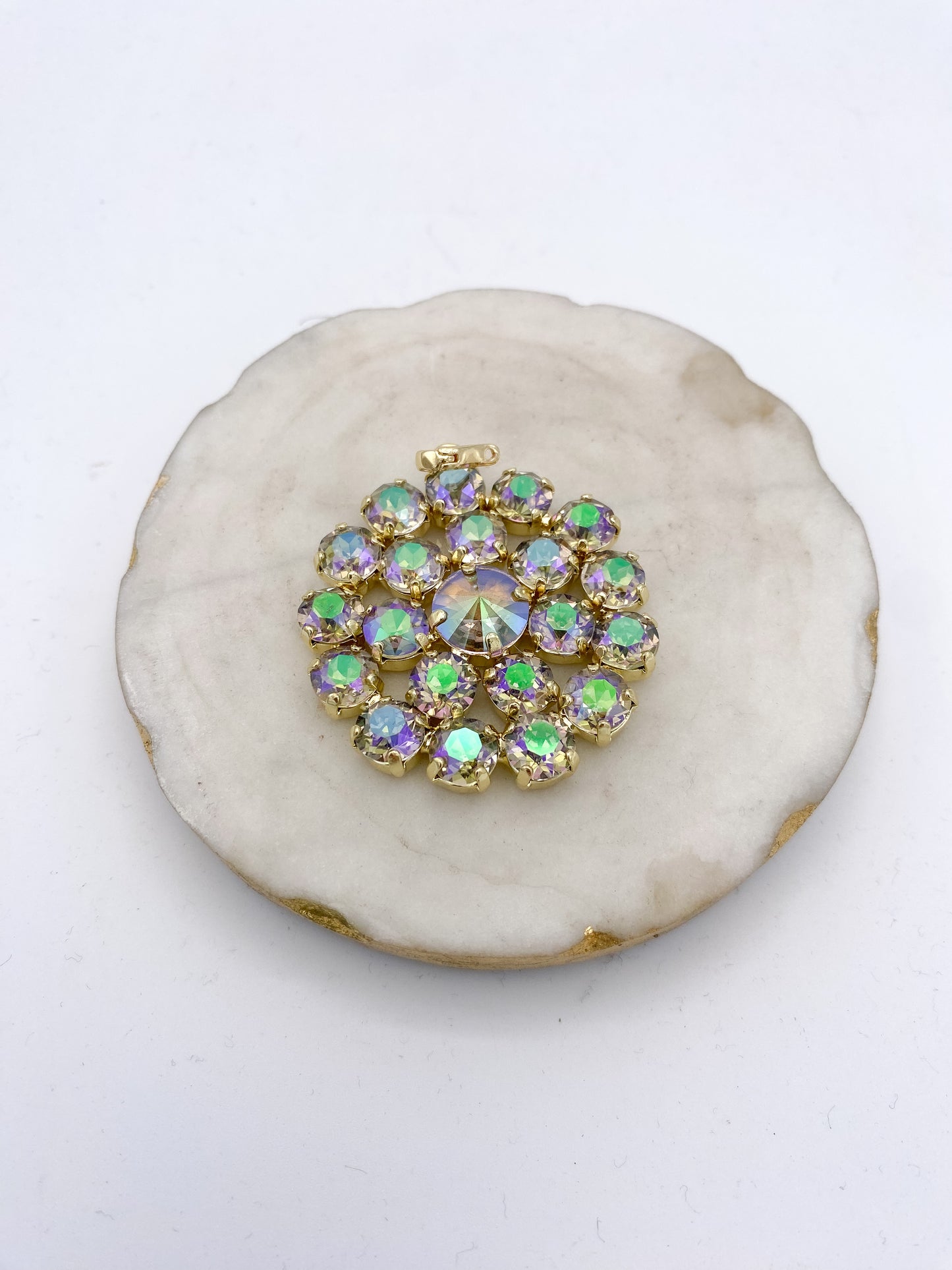 Gold-tone circular cluster pendant with iridescent purple and green AB rhinestones in a floral burst design