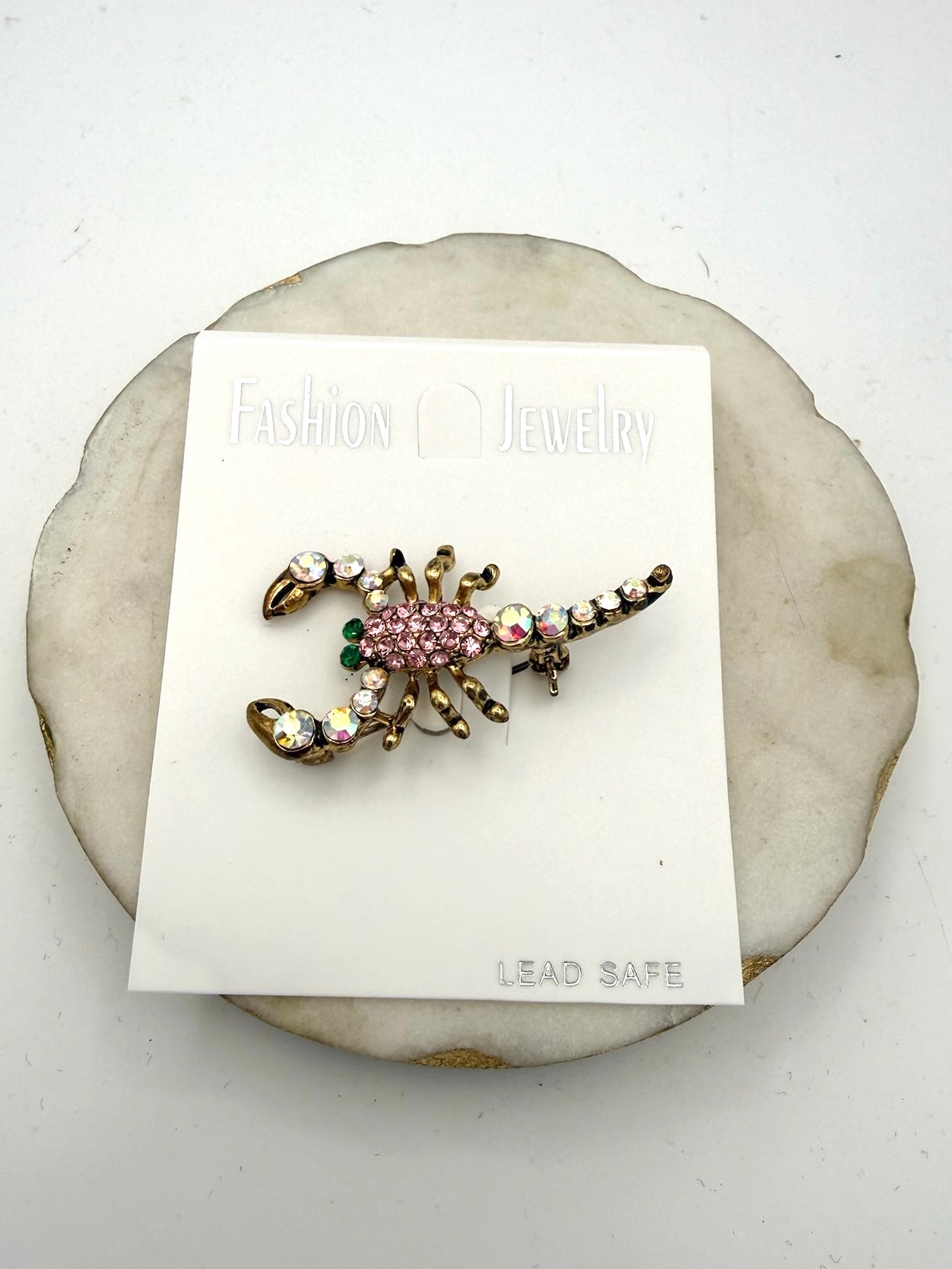 Gold-toned scorpion brooch with pink pavé crystals, iridescent AB rhinestones, and green eye accents.