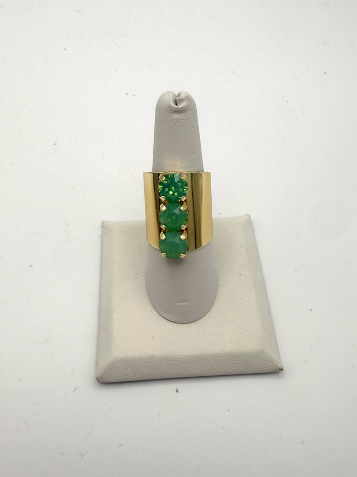 Wide gold cigar band ring with three vertical round-cut jade green gemstones in prong settings