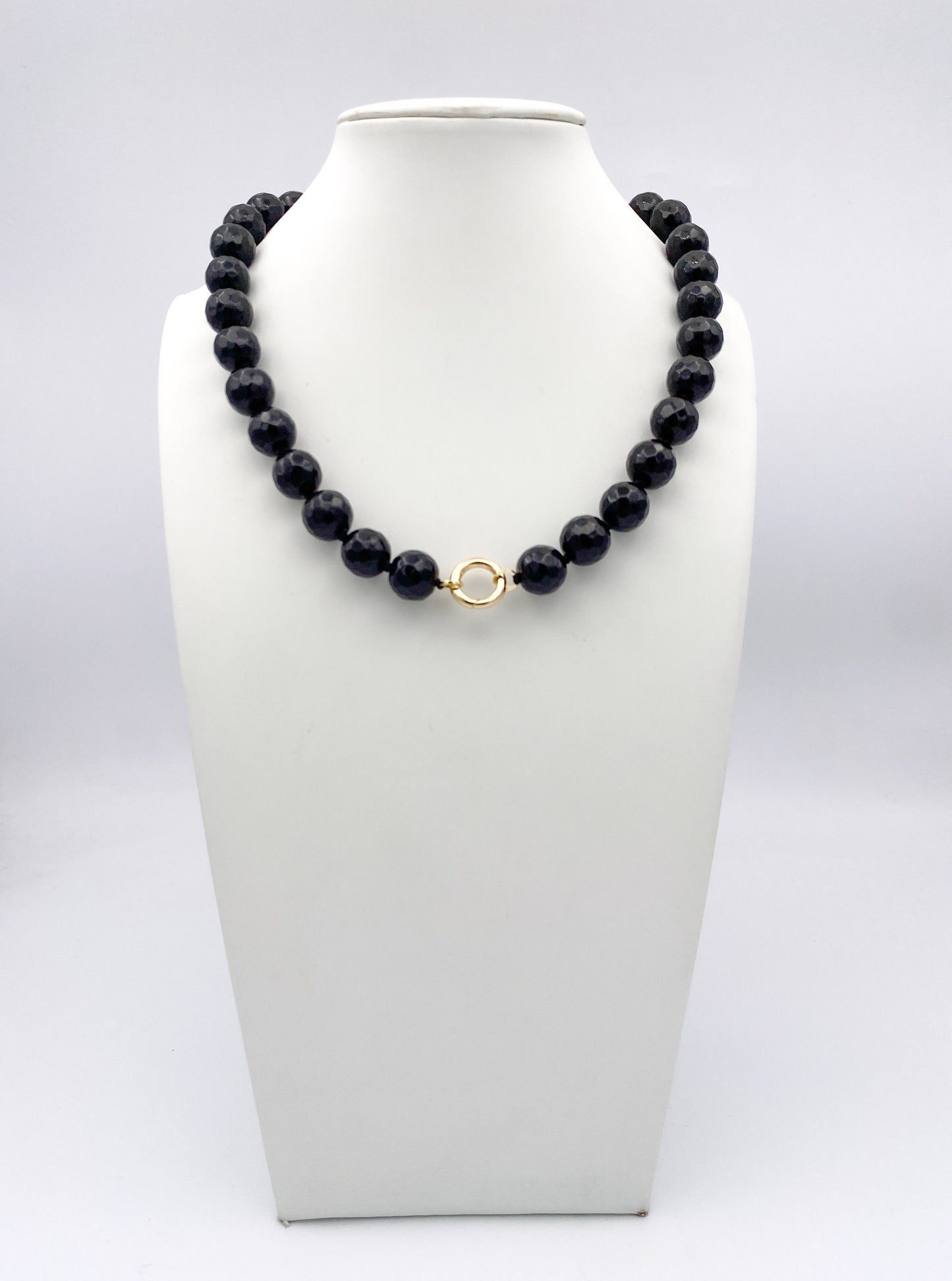 AF Designs Midnight Noir faceted dark navy bead necklace with gold circular clasp on white jewelry bust