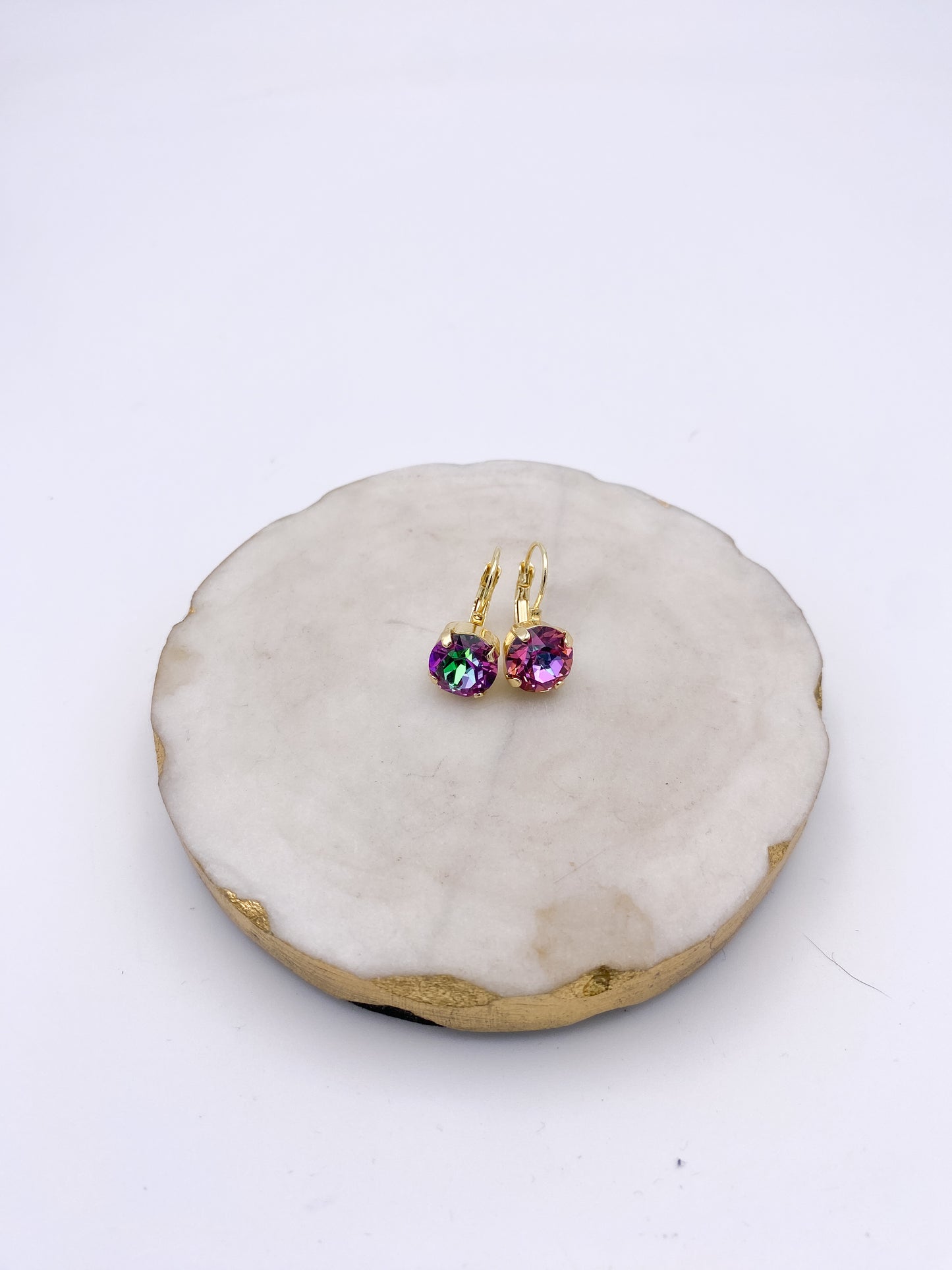 Gold lever-back drop earrings with iridescent violet-pink round crystal stones, color-shifting with green and rose flashes.