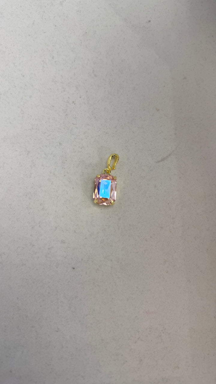 Small blush pink emerald-cut crystal charm pendant with gold prong setting and iridescent blue reflection