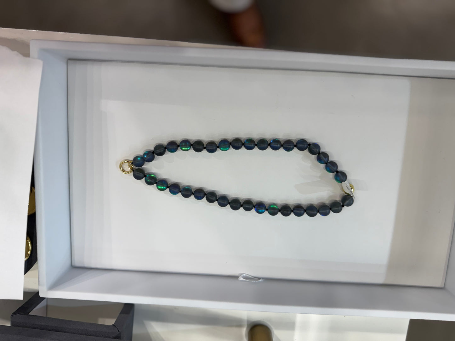AF Designs 10MM iridescent dark navy beaded necklace with gold clasp in Thunderstorm colorway, displayed in white box.
