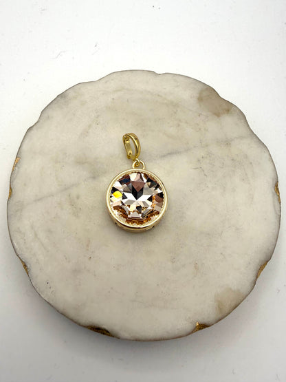 Round faceted champagne topaz crystal charm pendant in gold bezel setting with serrated edge detail and oval bail.