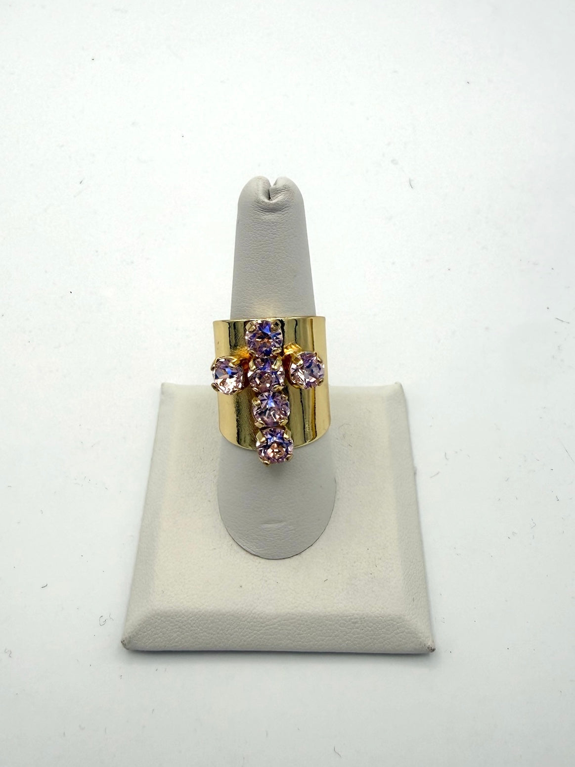 Wide gold cuff ring with cross-shaped baby pink and lavender rhinestone arrangement on white display stand
