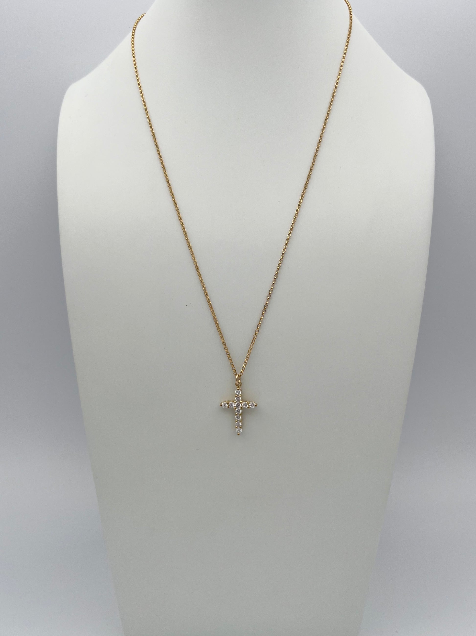 Gold chain necklace with crystal cross pendant displayed on white jewelry bust