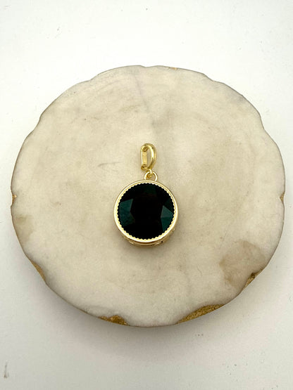 Round gold charm pendant with faceted black/dark green gemstone and decorative milgrain bezel setting.