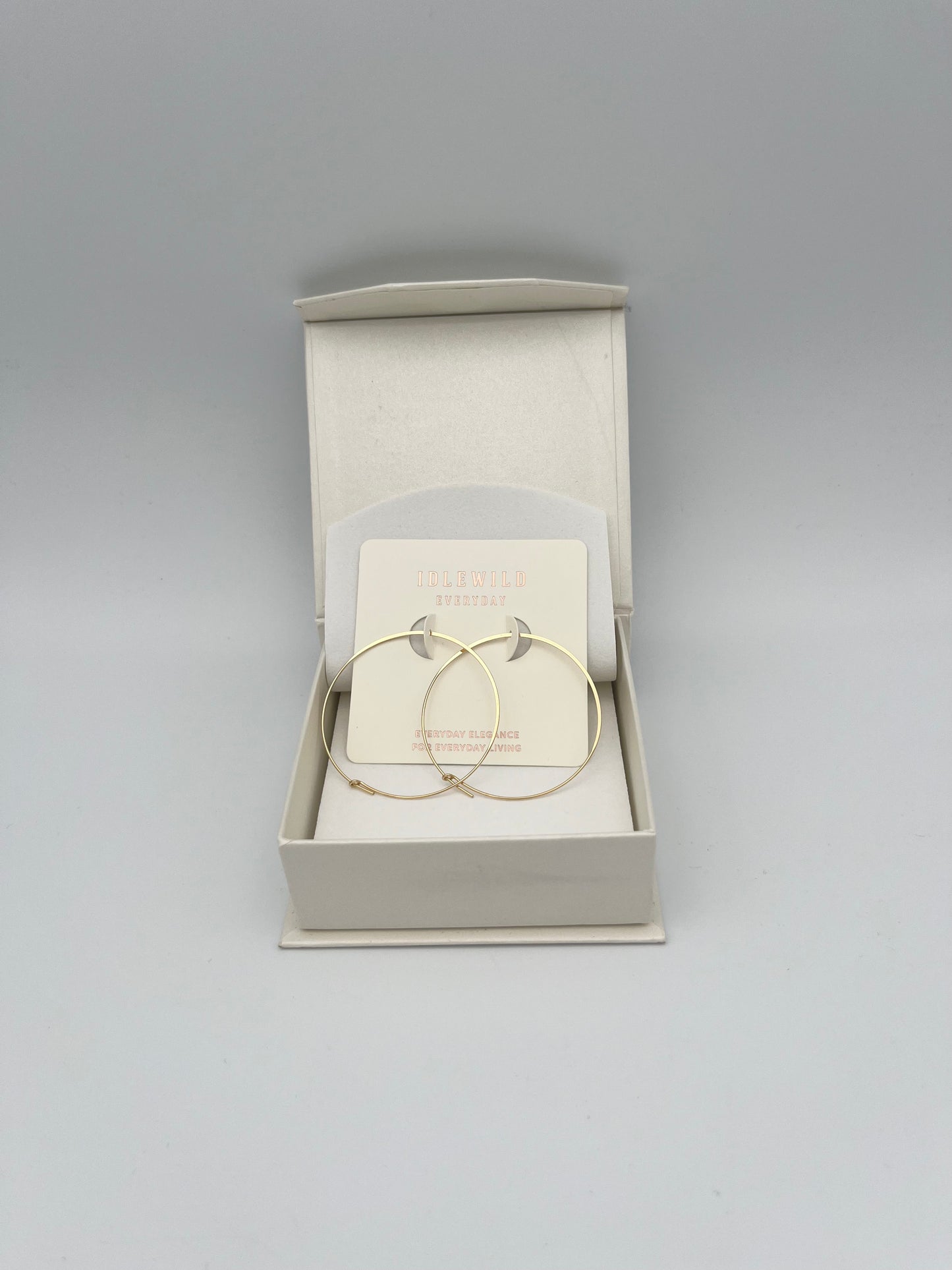 Gold hoop earrings in cream jewelry box from Idlewild Everyday brand