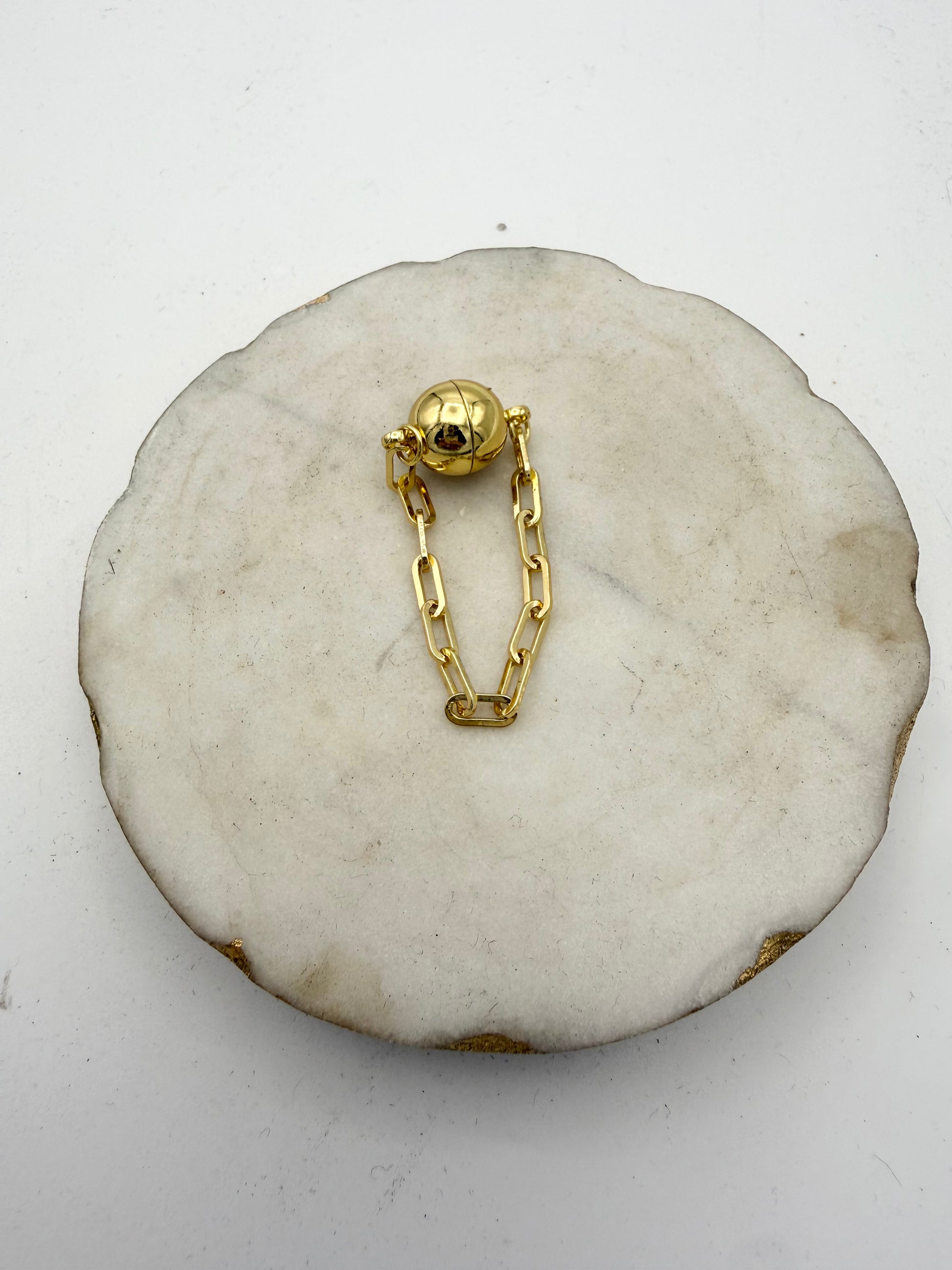 4-inch gold magnetic jewelry extender with spherical clasp and paperclip chain links on marble display