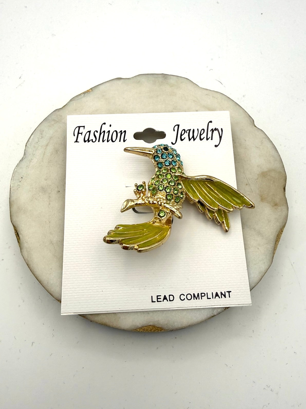 Gold-tone hummingbird brooch with aqua and peridot green rhinestones and enamel wings on retail card