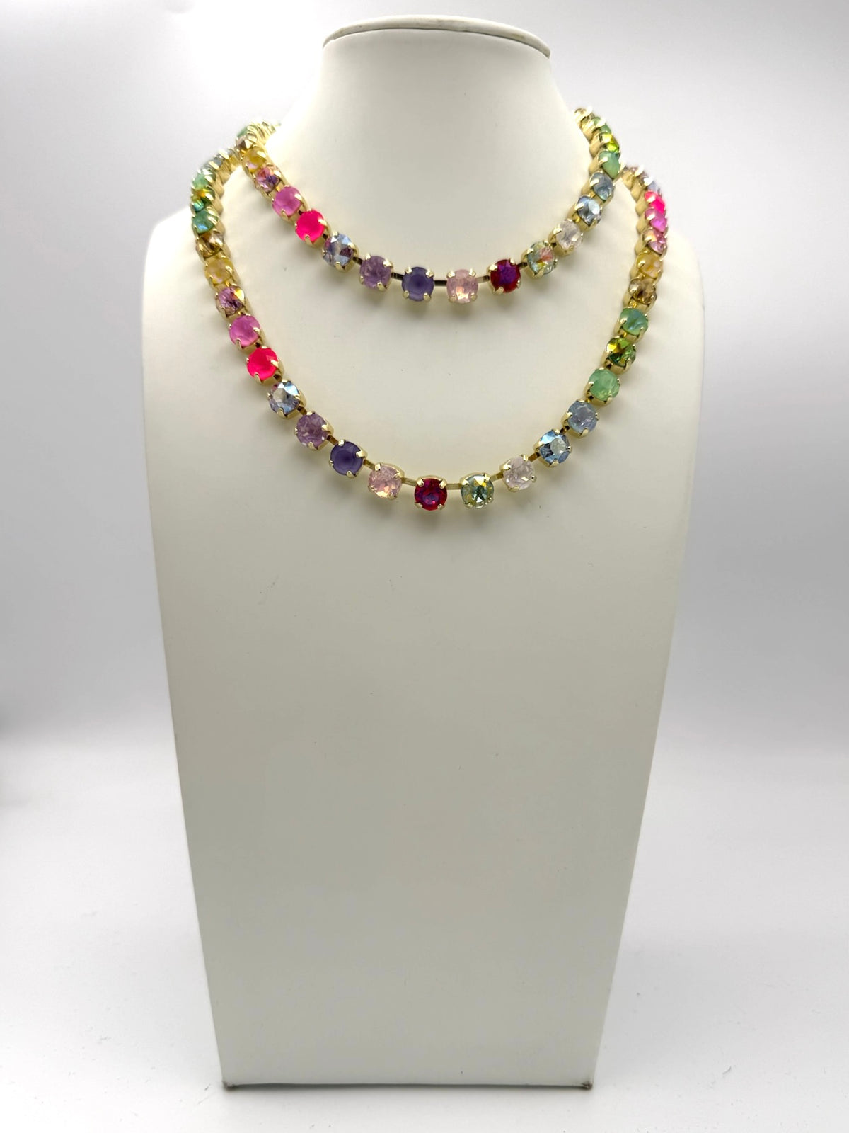Layered multicolor crystal tennis necklaces in gold-tone settings featuring rainbow rhinestones in two lengths.