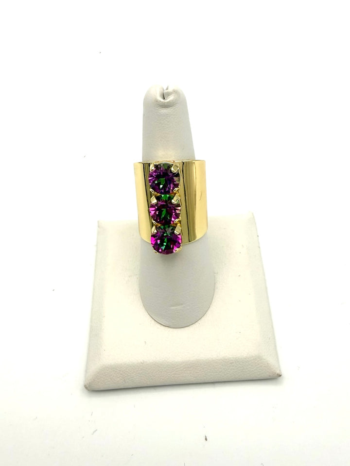 Wide gold-band cocktail ring with three vertical purple-fuchsia color-shifting round gemstones in prong settings