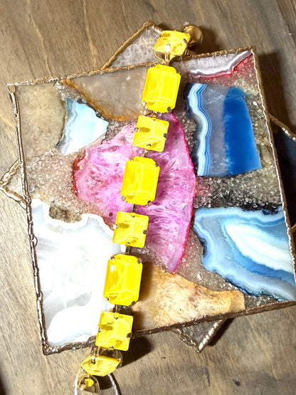 AF Designs yellow rectangular gemstone statement bracelet with gold prong settings on colorful agate display tray.