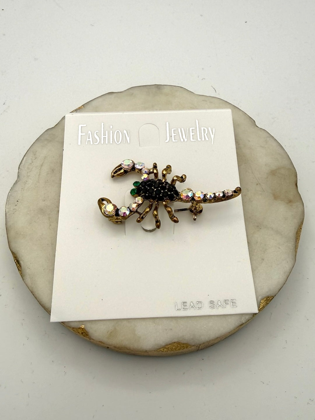 Scorpion brooch with black rhinestone body, AB crystal accents, and antique gold metal on retail card
