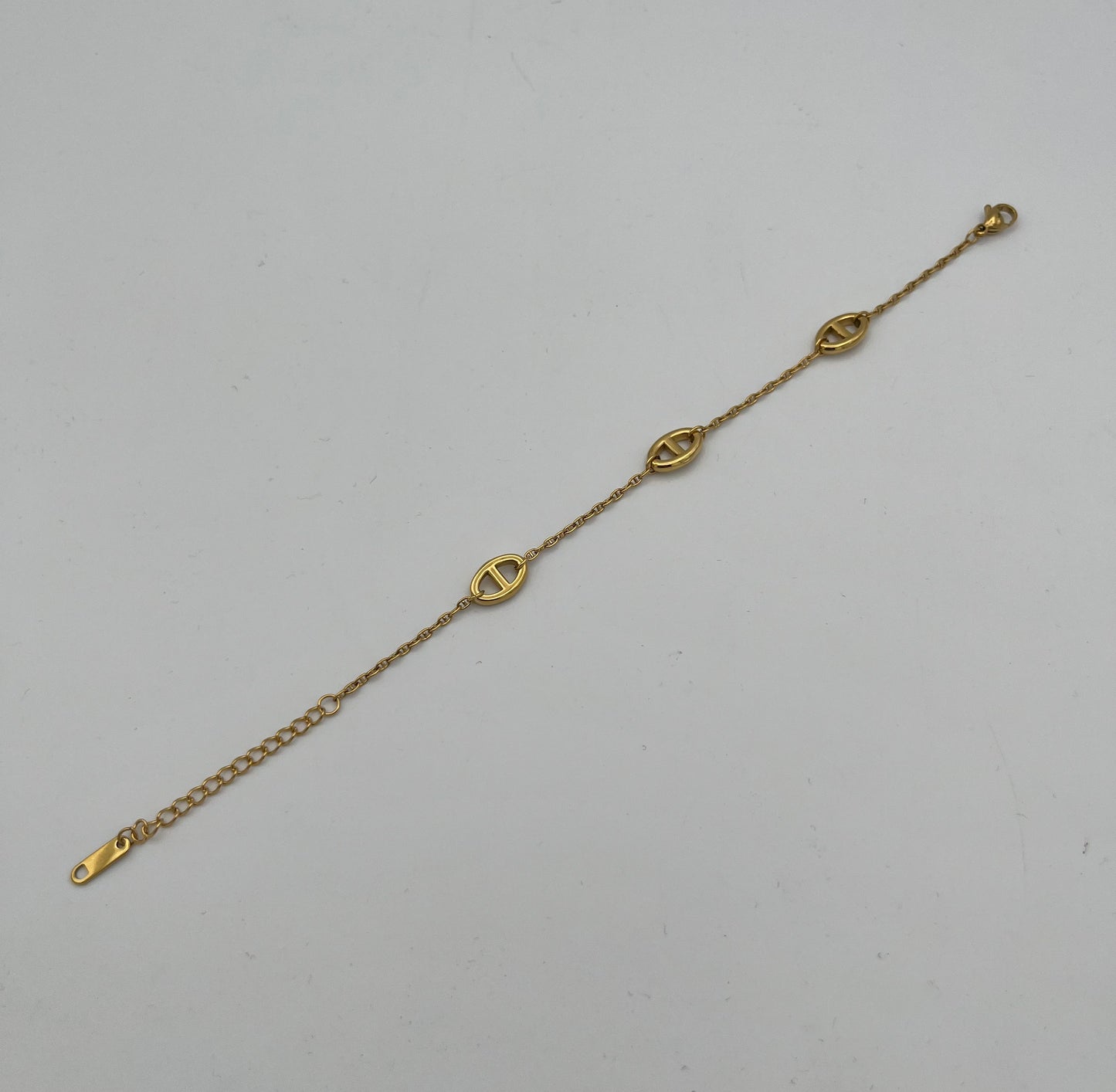 Gold chain bracelet with three oval cutout charms and adjustable extender
