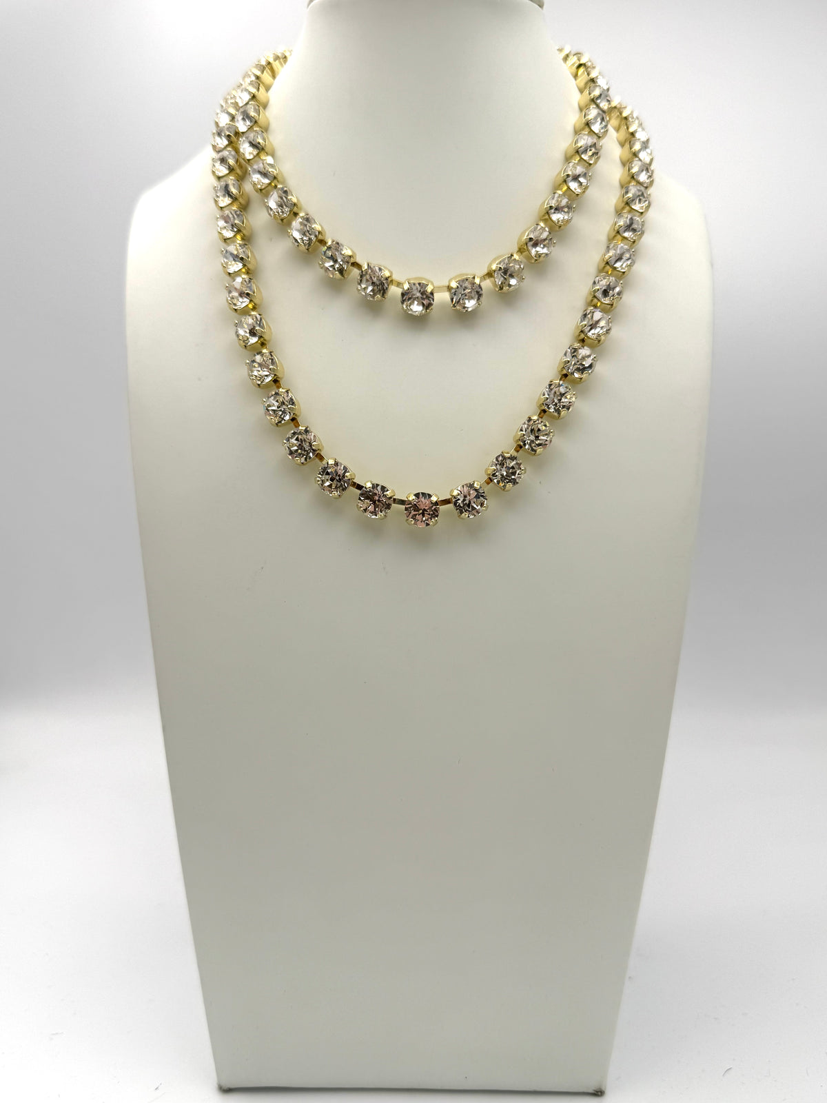 Double-strand gold tennis necklace with clear and champagne rhinestones in prong settings on jewelry bust