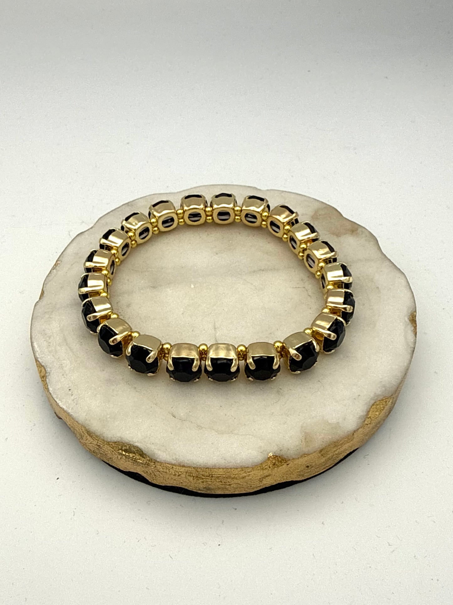 Gold-tone stretch tennis bracelet with 8mm cushion-cut black gemstones in prong settings with beaded accents.