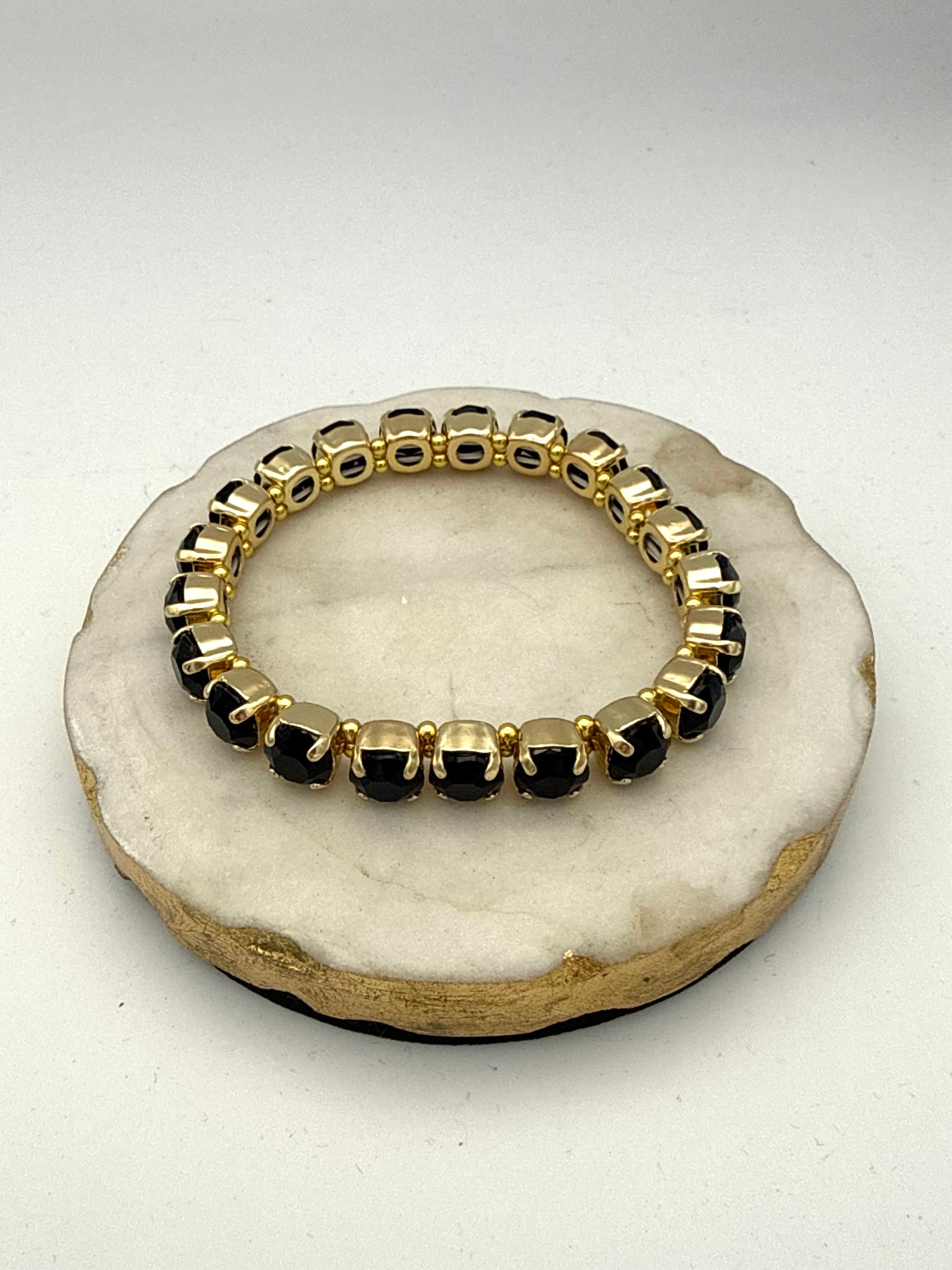 Gold-tone stretch tennis bracelet with 8mm cushion-cut black gemstones in prong settings with beaded accents.
