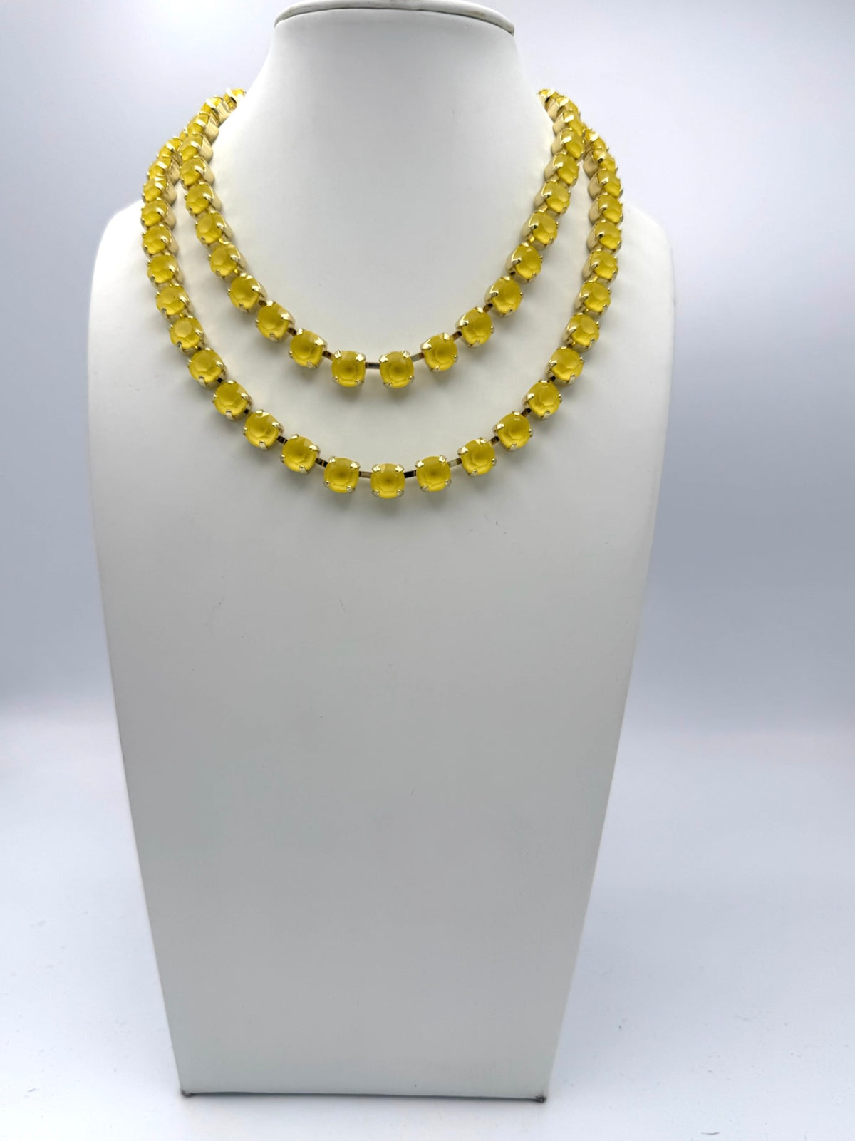 Double-strand yellow cabochon statement necklace with gold prong settings displayed on white jewelry bust