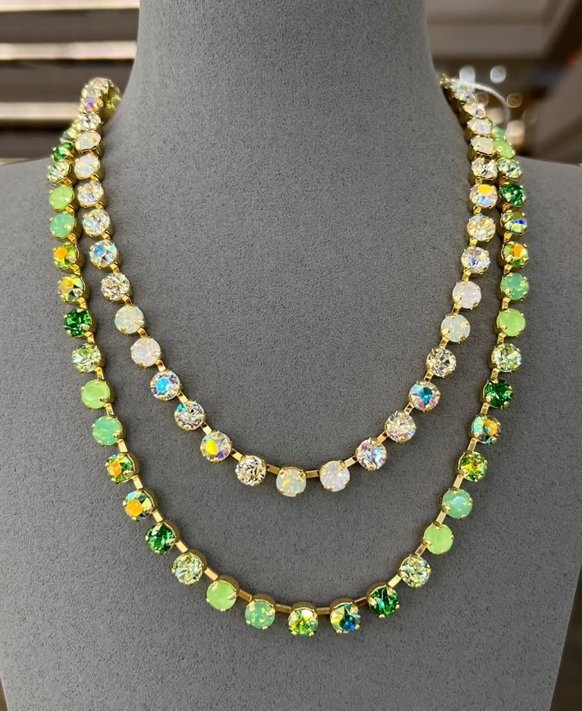 Two layered crystal tennis necklaces in gold setting - one with clear stones, one with green mixed crystals