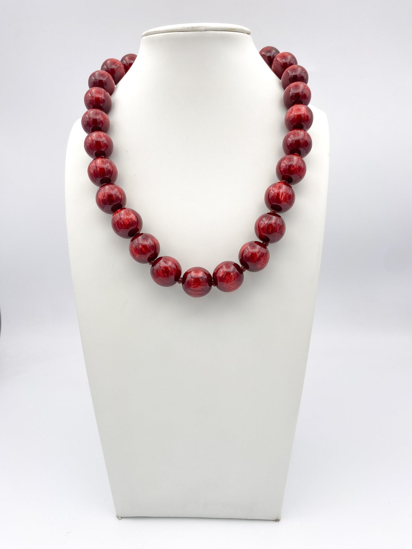 Large marbled burgundy wine round bead statement necklace with glossy finish on white jewelry bust