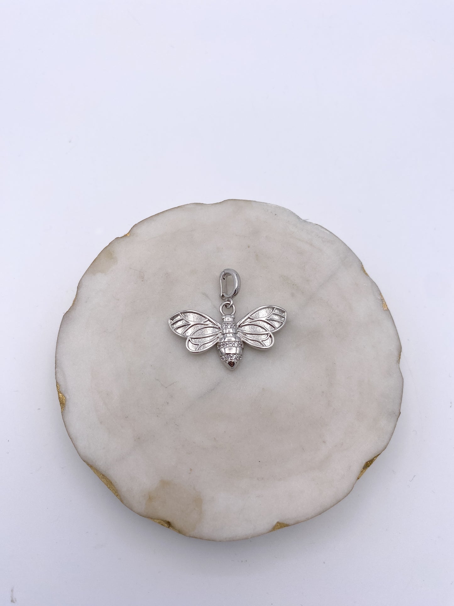 Silver bee charm pendant with filigree wings, pavé CZ body, and red gemstone tip by AF Designs