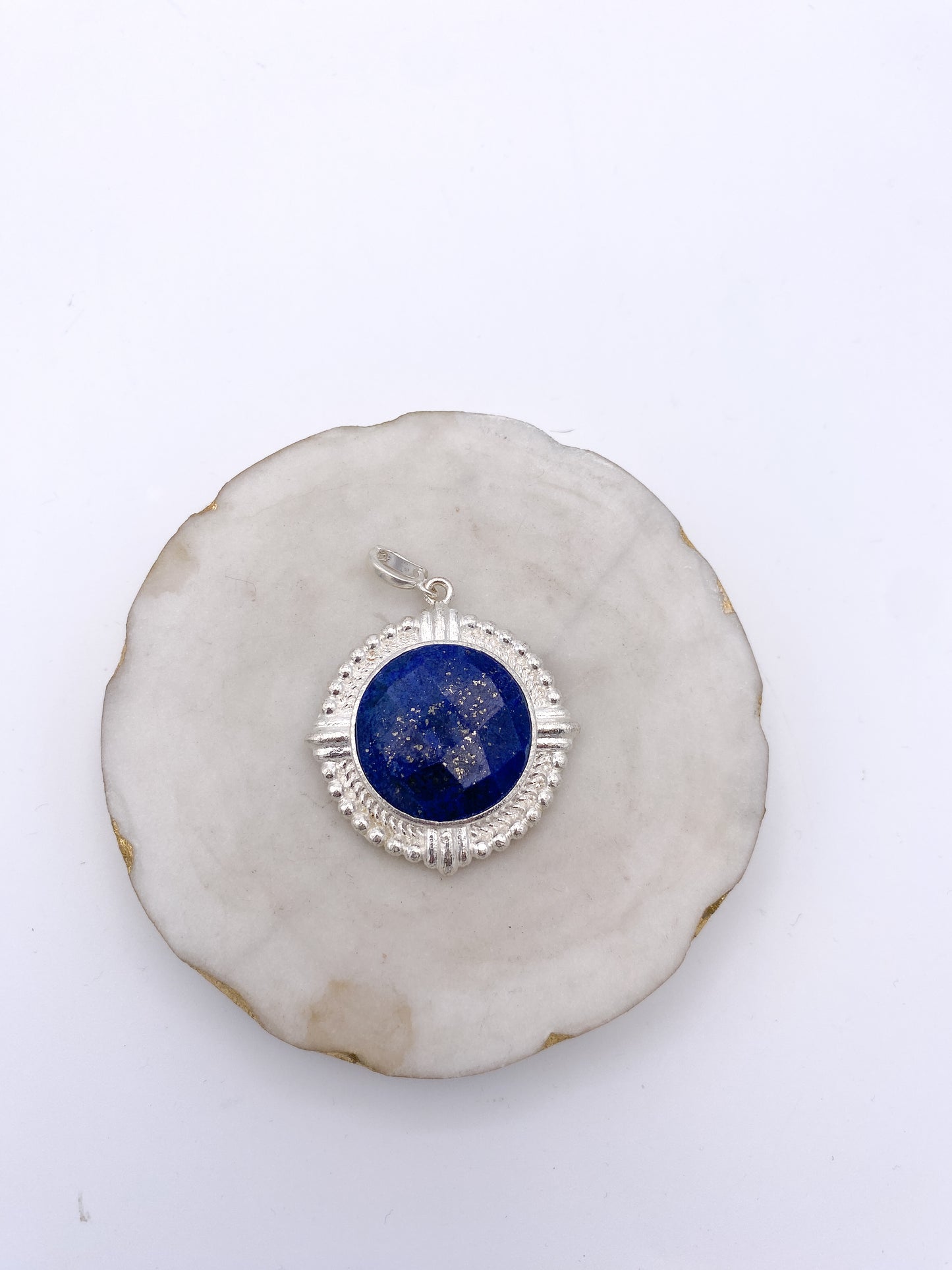 Round lapis lazuli pendant with silver ornate bezel frame, featuring gold pyrite flecks and decorative beaded border.