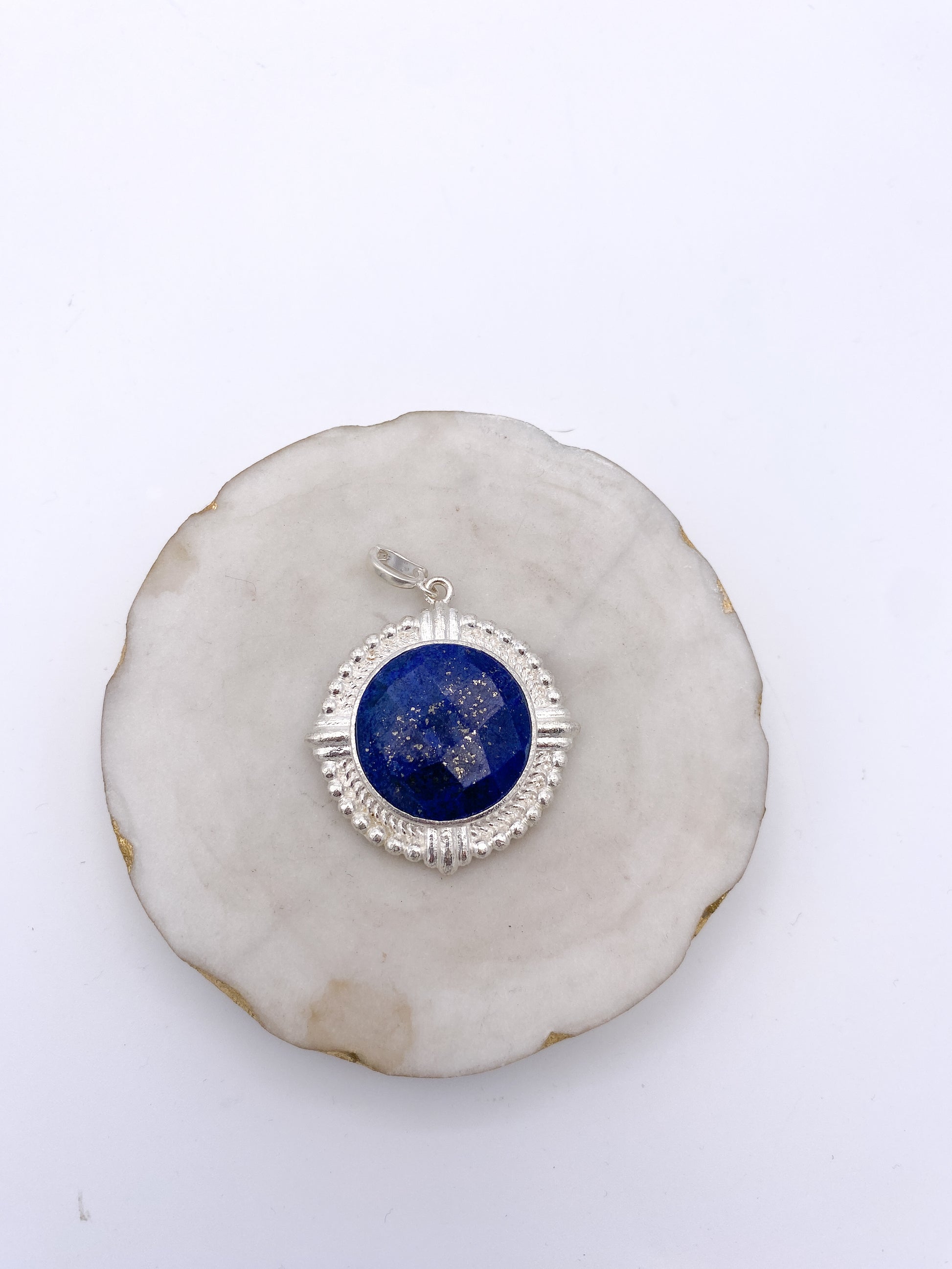Round lapis lazuli pendant with silver ornate bezel frame, featuring gold pyrite flecks and decorative beaded border.
