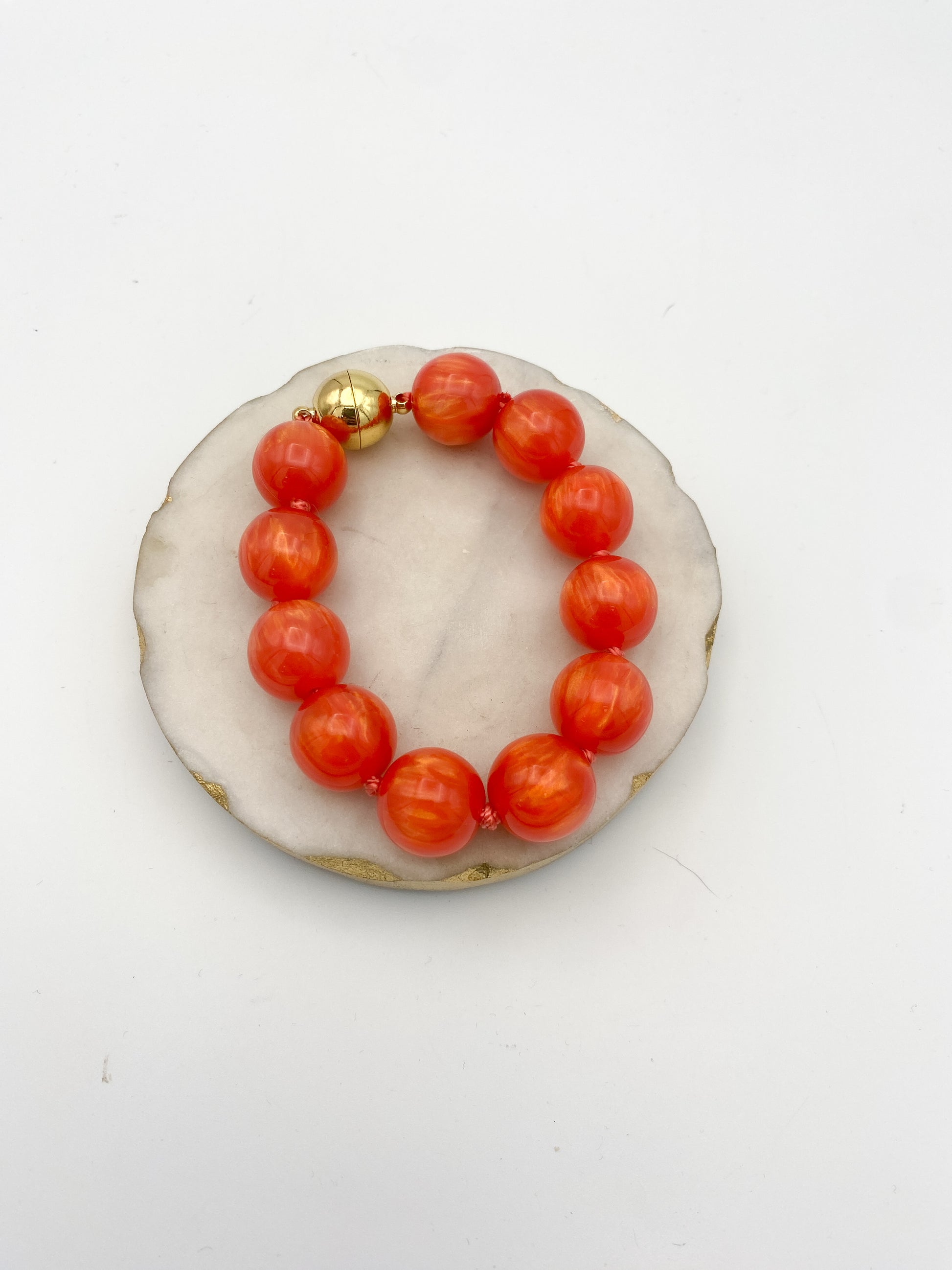 Going Places Bracelet: large coral orange marbled resin beads knotted on red cord with gold magnetic clasp.