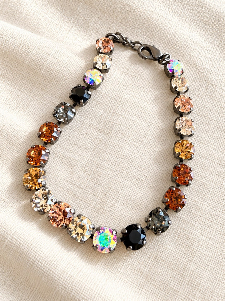Gunmetal tennis bracelet with mixed warm-toned crystals in amber, orange, black, and iridescent hues by AF Designs