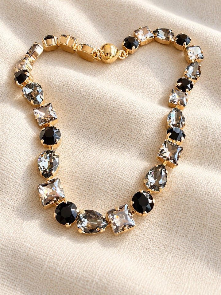 Gold statement necklace with mixed black, smoky grey, and clear crystal stones in varied cuts
