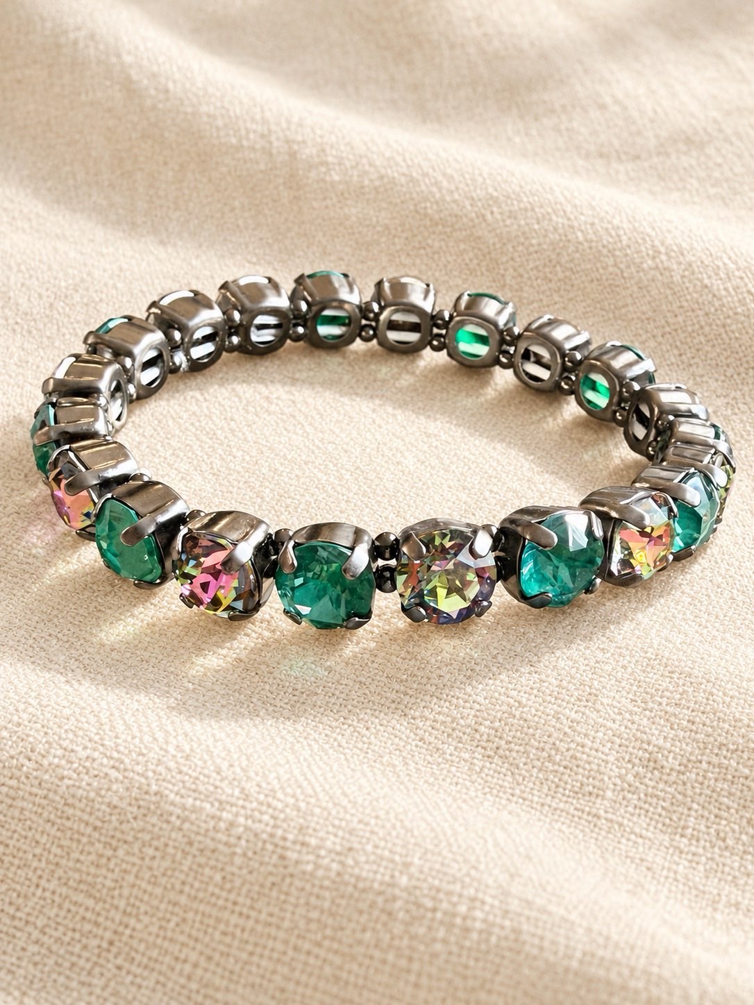 Drama Club stretch bracelet with alternating emerald green and iridescent rainbow crystals in gunmetal settings