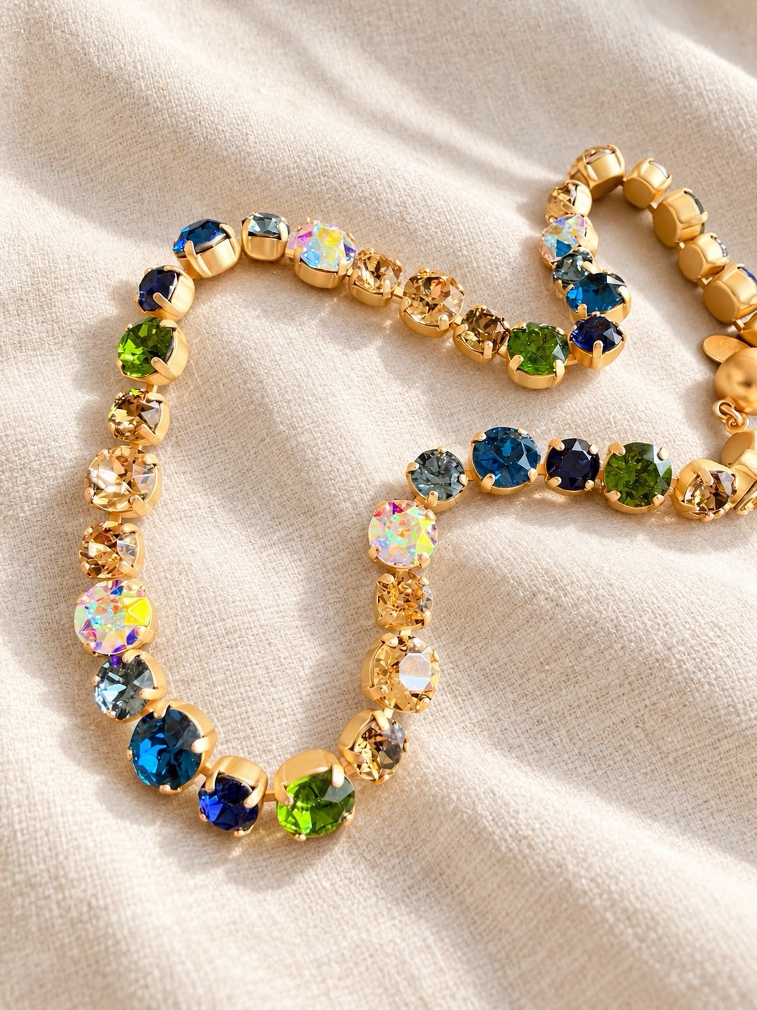 AF Designs gold tennis necklace with multicolor crystals in blue, green, aurora borealis, and champagne tones.