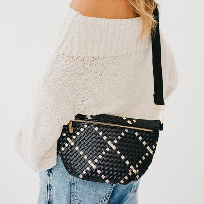 Black woven fanny bag with gold metallic diamond pattern, gold zipper, worn crossbody over cream sweater and jeans.