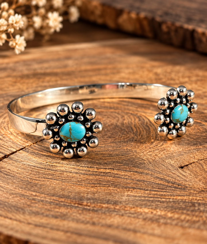 Boho Sol Turquoise Blossom Cuff, a sterling open cuff with turquoise stones ringed by silver beads on each end, on wood